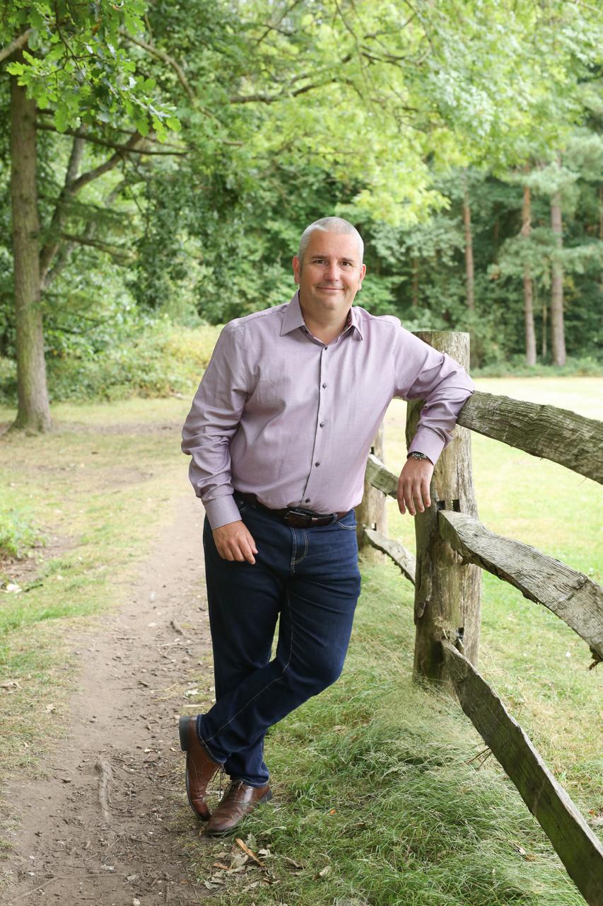 Brett Sheldon beside a wooden fence in a woodland setting