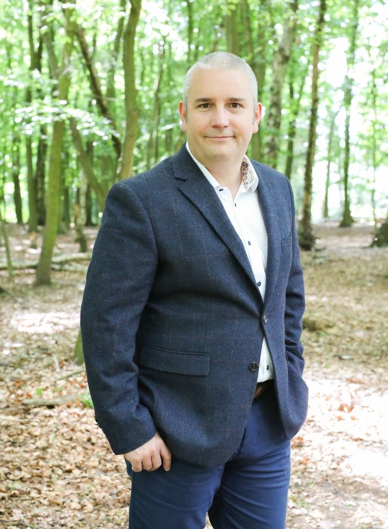 Brett Sheldon standing in a leafy woodland